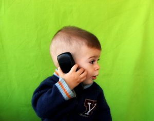 A young child on a phone communicating to a family member