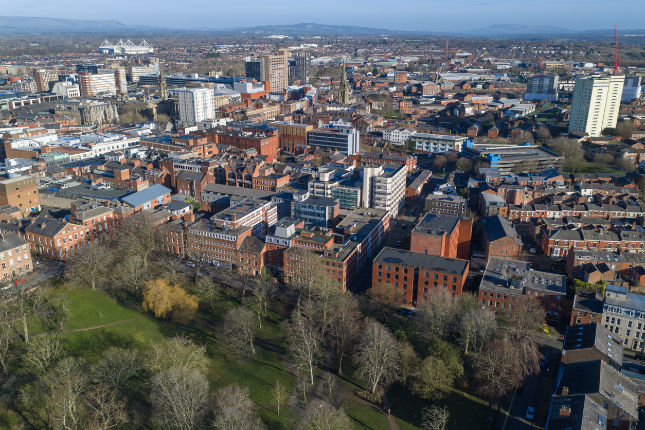 Aerial view of Preston, Lancashire, featuring the historic Winckley Square gardens in the foreground and the dense urban architecture of the city center.